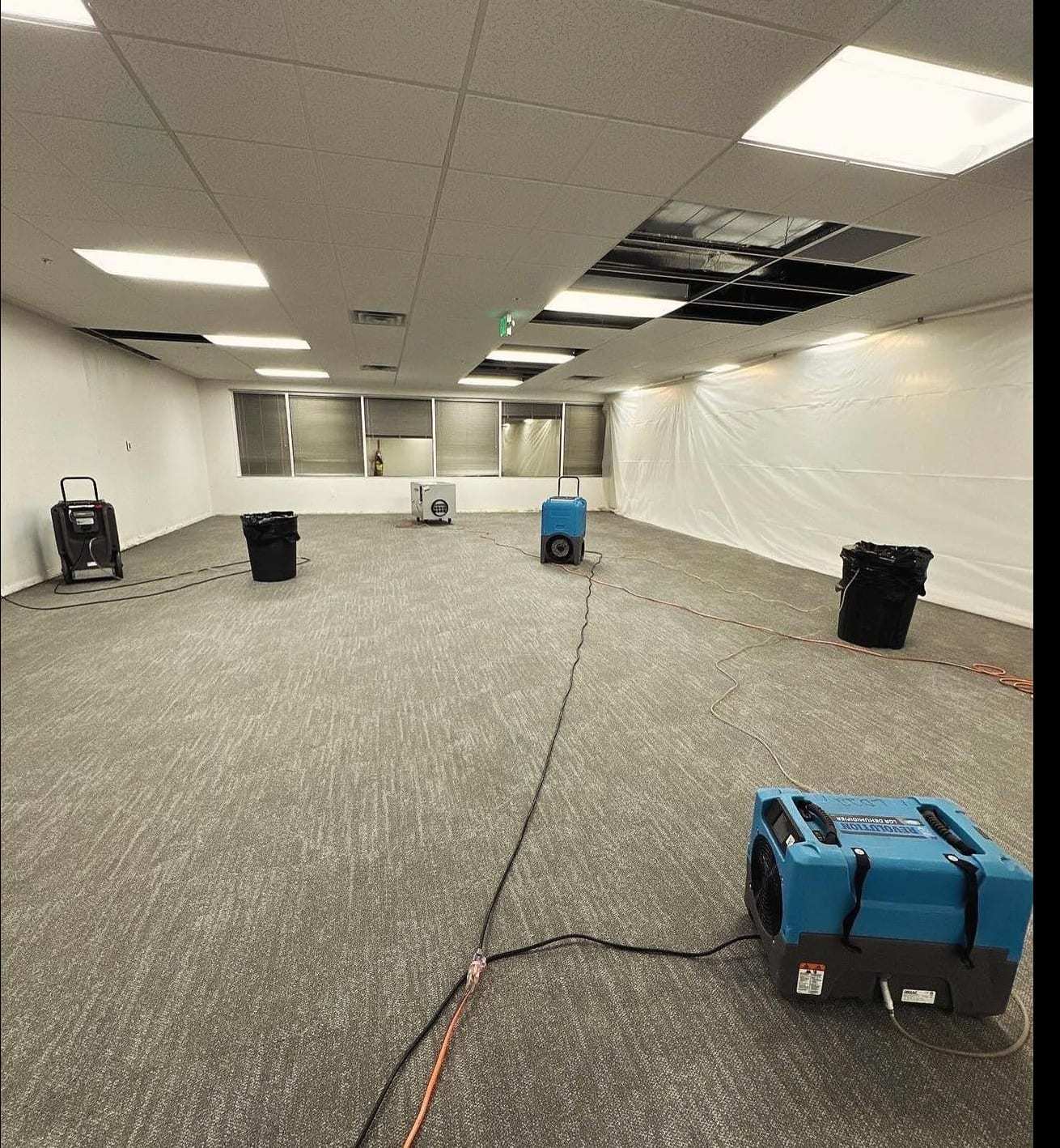 Empty office with containment and dehumidifiers drying the carpet