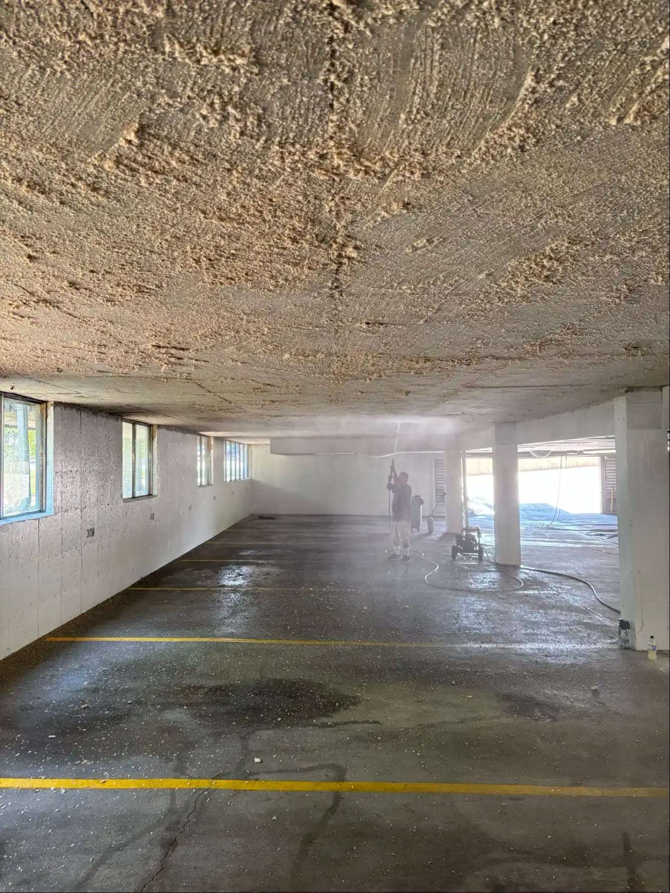 Wet floor of a parking garage with standing water along the stalls